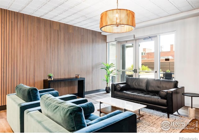 living area with wood finished floors, wood walls, and french doors