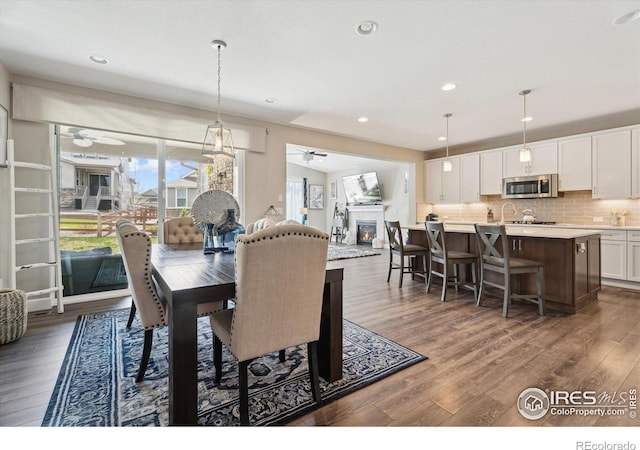 25190 E Nova Pl, Aurora, CO 80016 - dining space with ceiling fan, healthy amount of natural light, dark wood-style floors, a glass covered fireplace, and recessed lighting