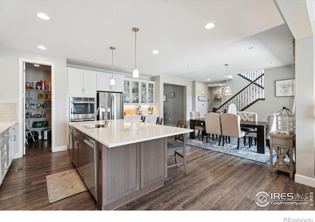 25190 E Nova Pl, Aurora, CO 80016 - kitchen featuring stainless steel appliances, a sink, dark wood finished floors, a spacious island, and white cabinets
