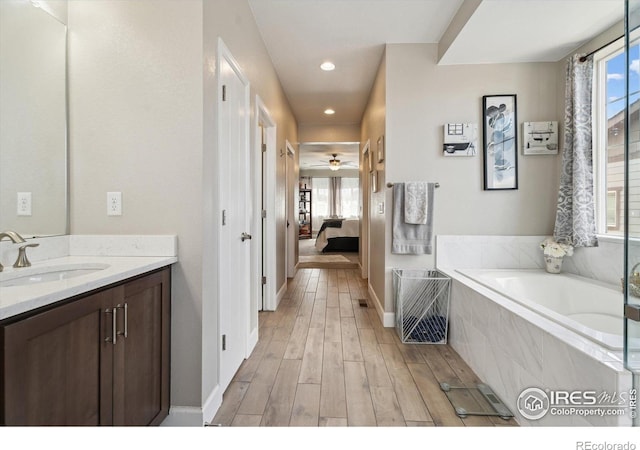 25190 E Nova Pl, Aurora, CO 80016 - ensuite bathroom featuring vanity, a bath, wood finished floors, a ceiling fan, and baseboards