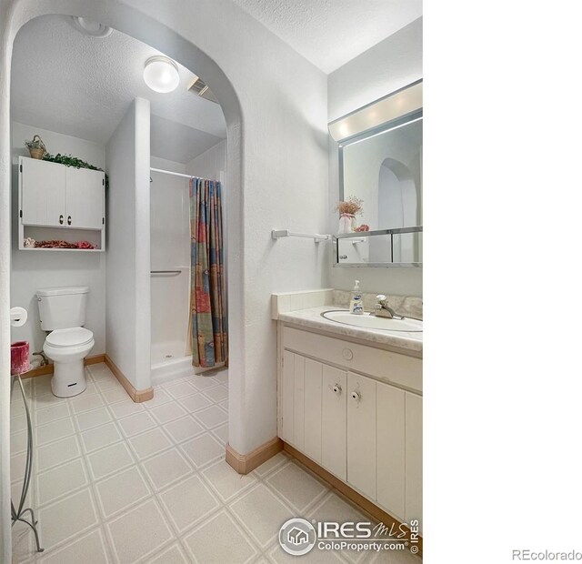 1145 S Bowman Ave, Holyoke, CO 80734 - full bath featuring tile patterned floors, a shower stall, a textured ceiling, toilet, and vanity