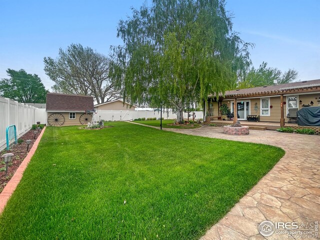 1145 S Bowman Ave, Holyoke, CO 80734 - view of yard featuring an outdoor structure, a storage unit, a patio area, and a wooden deck
