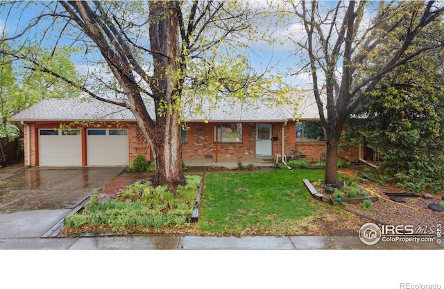 single story home with driveway, brick siding, an attached garage, and a front yard