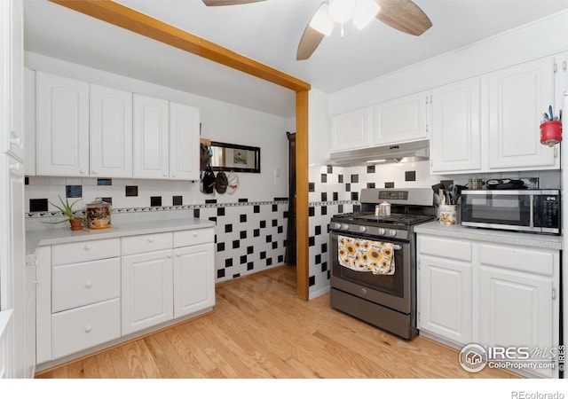 kitchen with appliances with stainless steel finishes, under cabinet range hood, ceiling fan, white cabinets, and light countertops