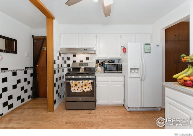 kitchen with stainless steel appliances, under cabinet range hood, light countertops, white cabinetry, and a ceiling fan