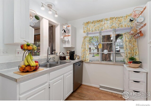 kitchen featuring stainless steel dishwasher, a sink, white cabinets, and light wood-style flooring