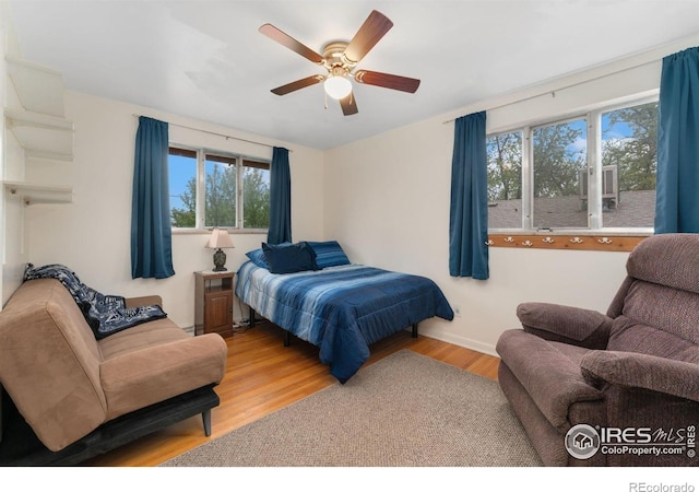 bedroom with multiple windows, wood finished floors, ceiling fan, and baseboards