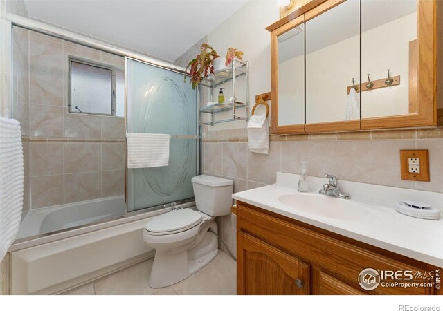bathroom featuring vanity, tile walls, toilet, enclosed tub / shower combo, and tile patterned floors