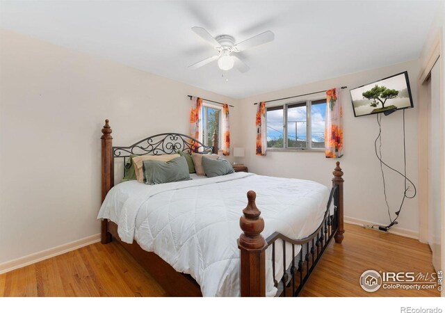 bedroom with light wood-style floors, baseboards, and ceiling fan