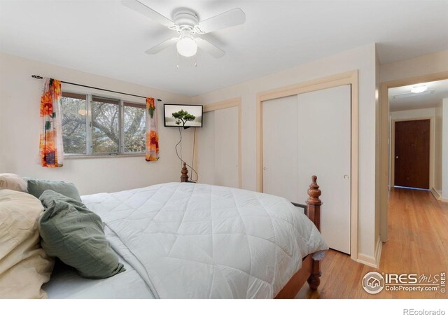 bedroom with light wood-style floors, two closets, ceiling fan, and baseboards
