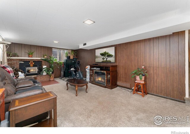 living room featuring a glass covered fireplace, wood walls, and carpet