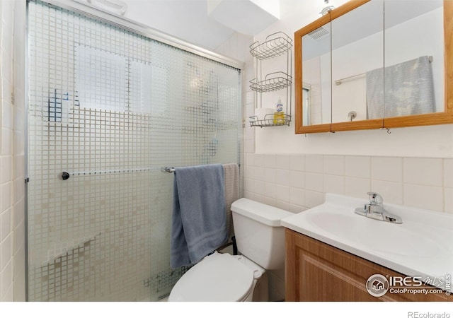 bathroom with tile walls, a shower stall, toilet, vanity, and decorative backsplash
