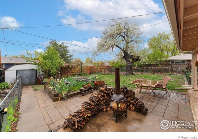 view of patio / terrace featuring a garden, a storage shed, and an outdoor structure