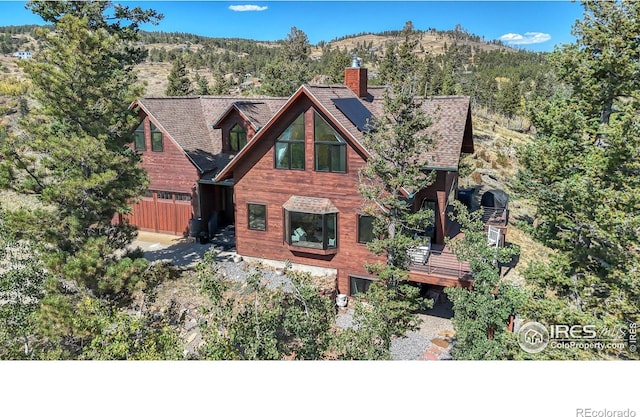 back of property with solar panels, a chimney, and a mountain view