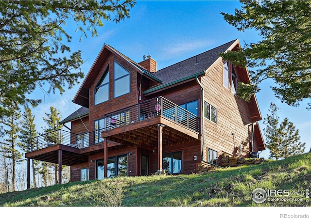 rear view of property with a deck and a chimney