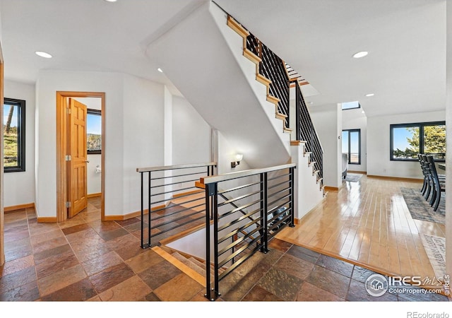staircase featuring baseboards, stone tile flooring, and recessed lighting