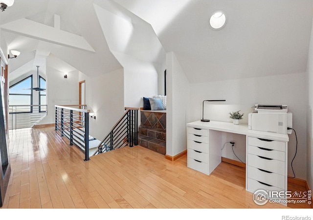 office area featuring vaulted ceiling, light wood-type flooring, and baseboards