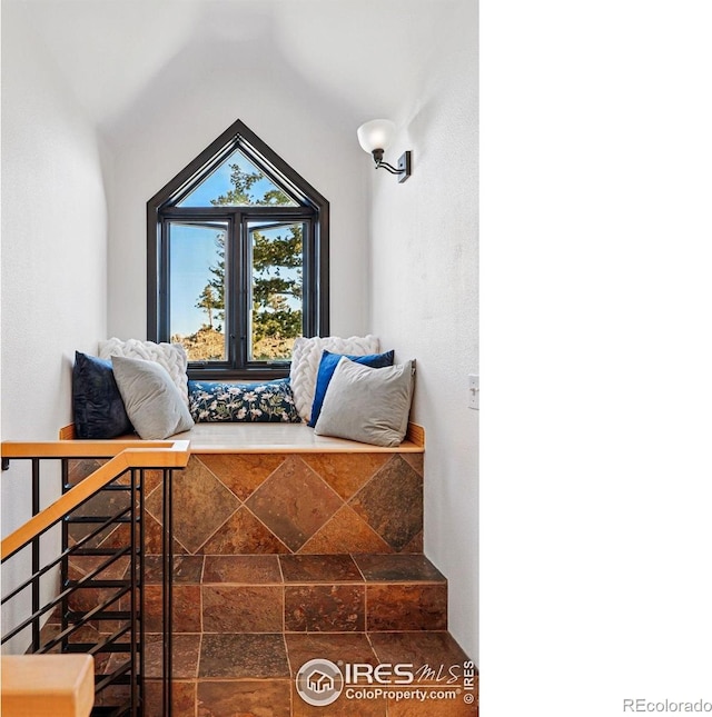 living area featuring stone finish flooring and lofted ceiling