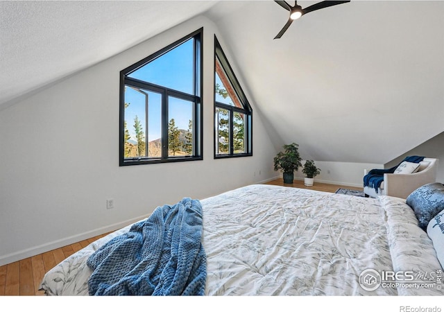 bedroom with vaulted ceiling, wood finished floors, baseboards, and ceiling fan