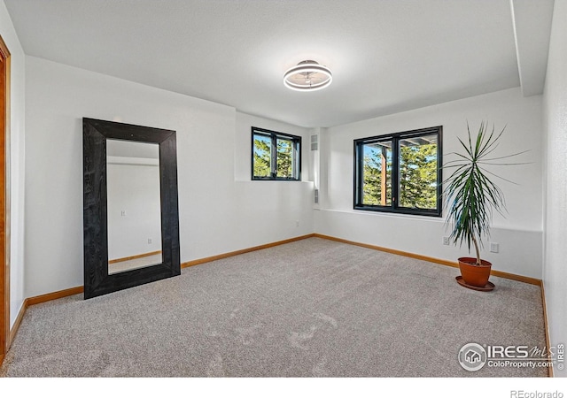 carpeted empty room featuring baseboards