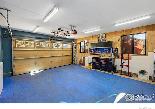 garage featuring a workshop area, wooden walls, and a garage door opener