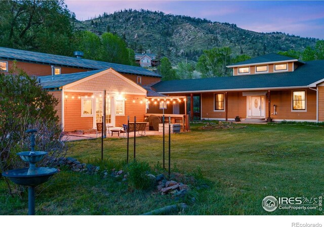 rear view of property with a yard, a mountain view, and a patio