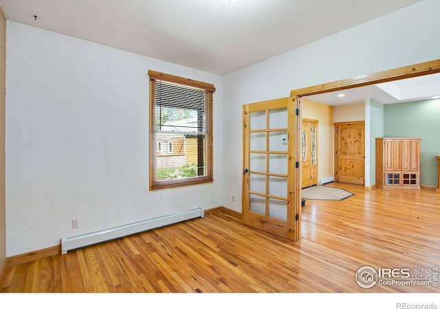unfurnished room with a baseboard radiator, wood finished floors, baseboards, recessed lighting, and french doors