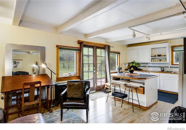 kitchen with white cabinetry, beamed ceiling, light wood-type flooring, decorative backsplash, and open shelves
