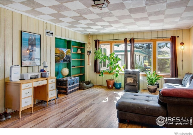 sitting room featuring wooden walls, wood finished floors, and crown molding