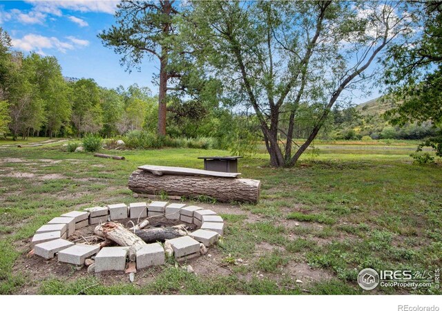 view of green lawn featuring an outdoor fire pit