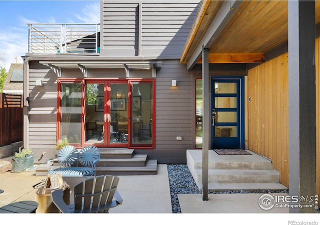view of exterior entry with french doors and fence