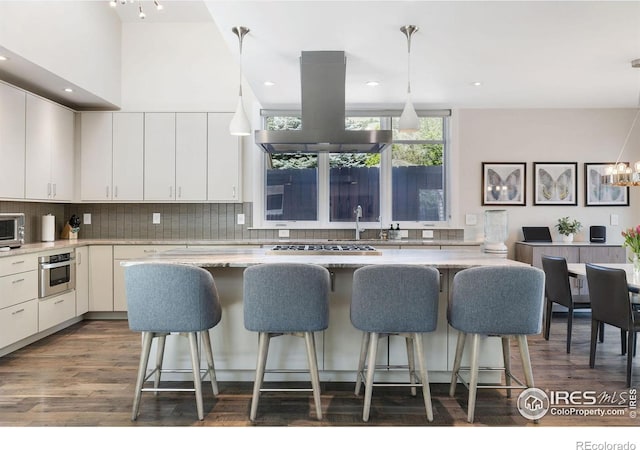 kitchen featuring island range hood, a breakfast bar, white cabinets, dark wood finished floors, and recessed lighting