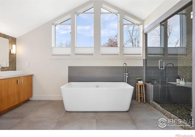 bathroom featuring vaulted ceiling, vanity, plenty of natural light, a freestanding bath, and a shower stall