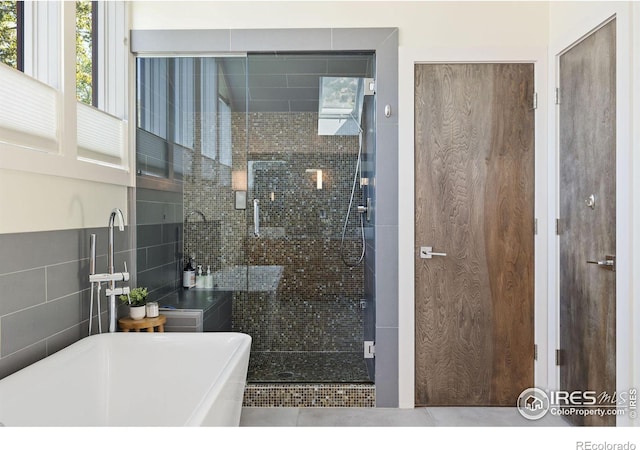 full bathroom featuring a stall shower, tile walls, a soaking tub, and tile patterned floors