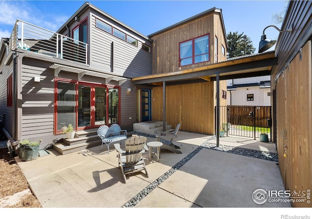 rear view of house featuring a balcony, a patio, a gate, and entry steps