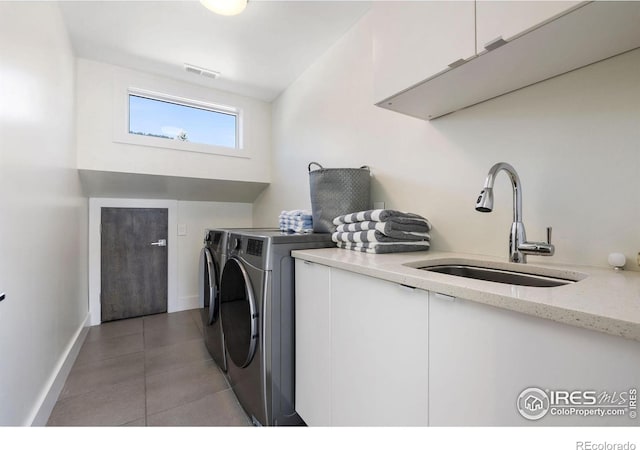 laundry area with cabinet space, separate washer and dryer, light tile patterned floors, and baseboards