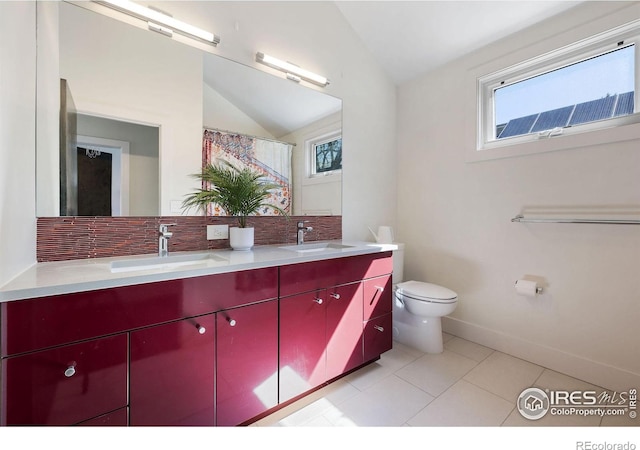 bathroom featuring vaulted ceiling, plenty of natural light, toilet, double vanity, and tile patterned flooring