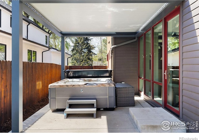wooden deck featuring a hot tub, fence, and a patio