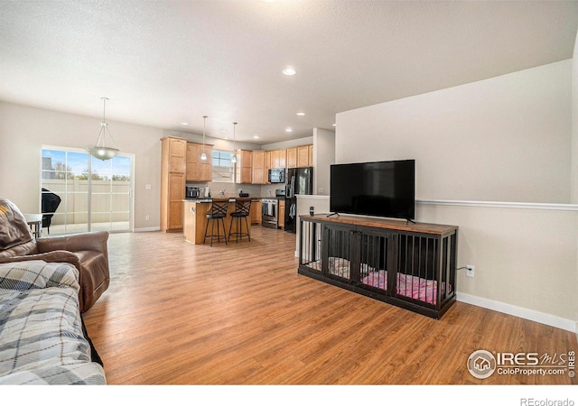 living area featuring light wood-type flooring, baseboards, and recessed lighting