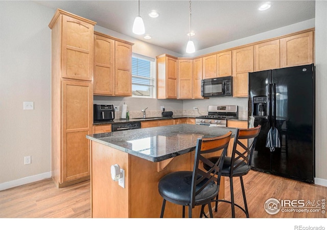 kitchen featuring black appliances, a sink, light wood finished floors, baseboards, and a center island
