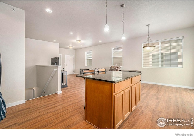 kitchen featuring light wood-style flooring, baseboards, a center island, recessed lighting, and pendant lighting