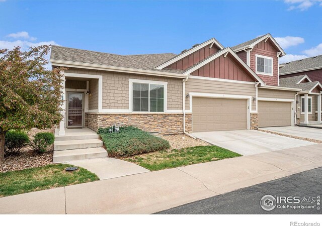 craftsman-style house featuring board and batten siding, stone siding, and driveway