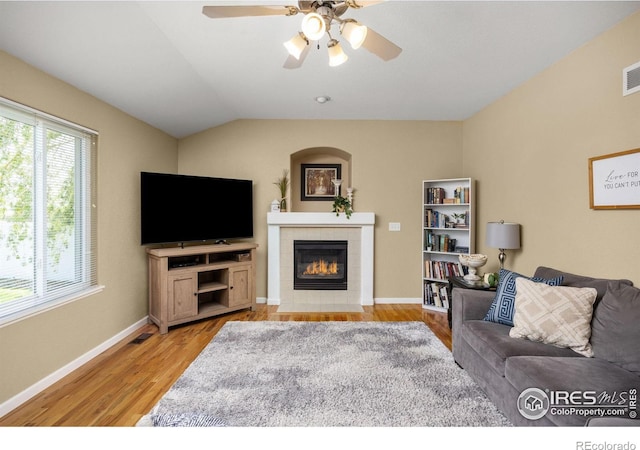 316 Whitney Bay, Windsor, CO 80550 - living room with a tiled fireplace, light wood-type flooring, a ceiling fan, vaulted ceiling, and baseboards