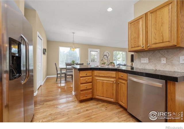 316 Whitney Bay, Windsor, CO 80550 - kitchen featuring stainless steel appliances, a peninsula, light wood-style floors, tasteful backsplash, and baseboards