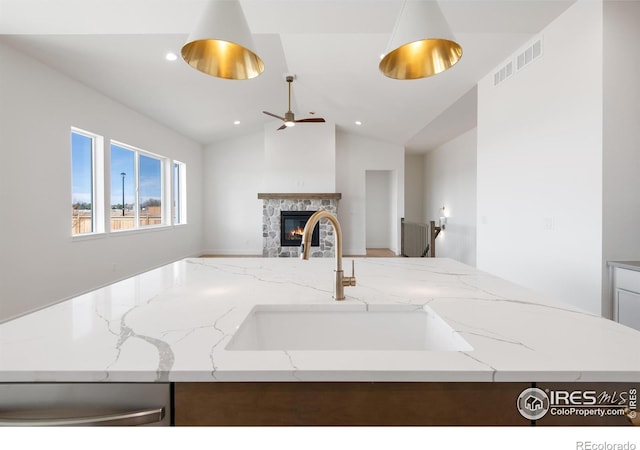 20 Snowcap Dr, Windsor, CO 80550 - kitchen featuring a sink, a ceiling fan, open floor plan, a stone fireplace, and light stone countertops