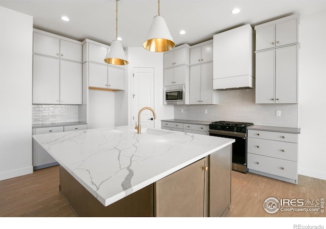 20 Snowcap Dr, Windsor, CO 80550 - kitchen with range with gas stovetop, stainless steel microwave, premium range hood, a sink, and white cabinetry