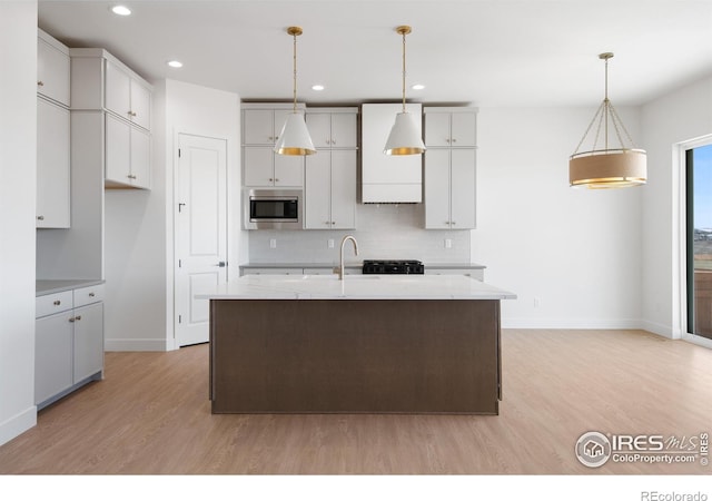 20 Snowcap Dr, Windsor, CO 80550 - kitchen featuring stainless steel microwave, baseboards, light wood finished floors, tasteful backsplash, and light stone counters
