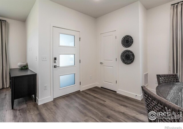 entrance foyer with dark wood-style flooring and baseboards