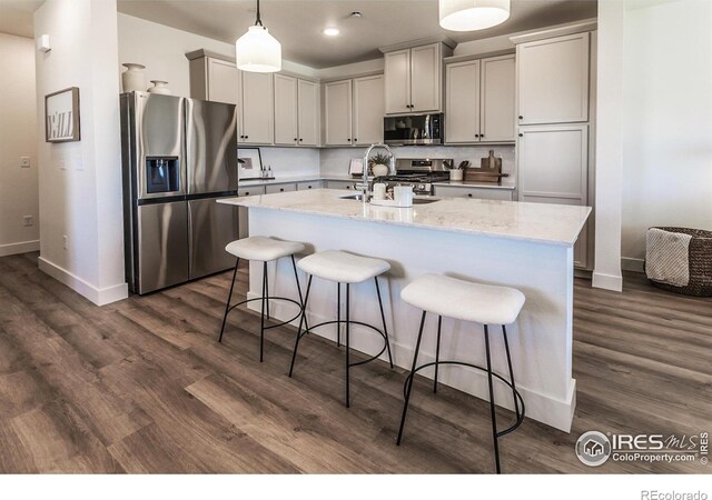 kitchen with appliances with stainless steel finishes, a sink, baseboards, a breakfast bar area, and recessed lighting