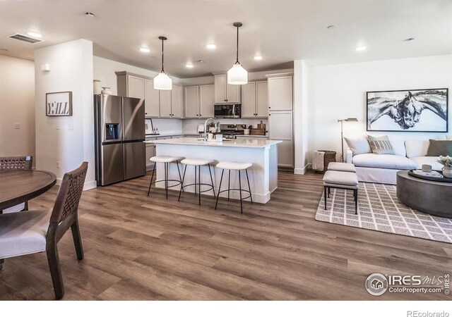 kitchen with appliances with stainless steel finishes, open floor plan, light countertops, a breakfast bar, and recessed lighting